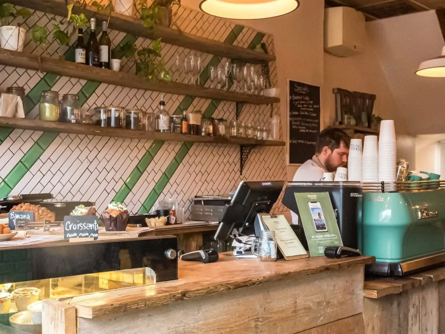 Brickwood cafe on Clapham Common Northside, with pavement tables and cyclists passing